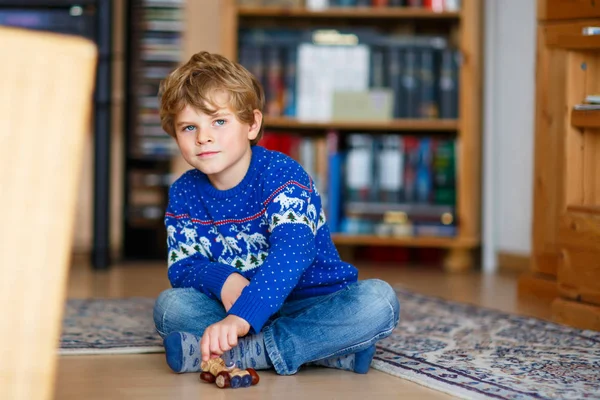 Menino brincando com brinquedo castanho artesanal dentro de casa — Fotografia de Stock