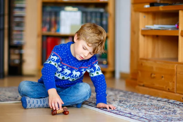 Маленький мальчик играет с каштановой игрушкой ручной работы в помещении — стоковое фото