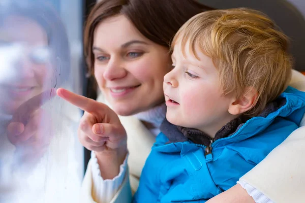 Lindo niño pequeño y madre mirando por la ventana del tren haciendo vacaciones de invierno —  Fotos de Stock