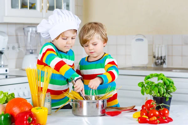 Два маленьких мальчика готовят макароны с овощами — стоковое фото