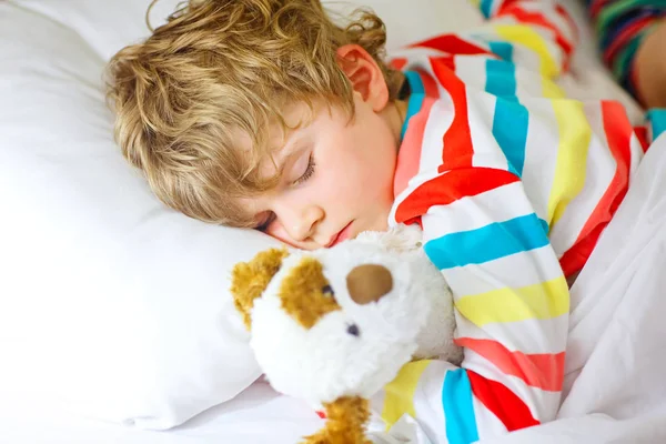 Маленька блондинка хлопчик в барвистому нічному одязі спить — стокове фото