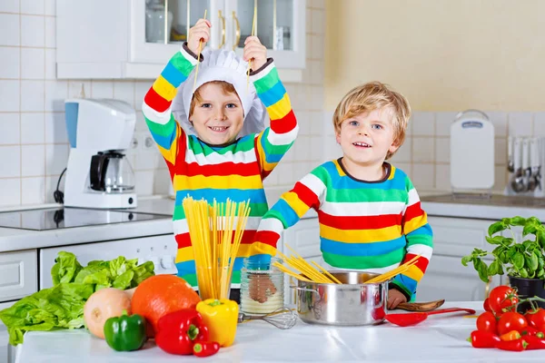 Два маленьких мальчика готовят макароны с овощами — стоковое фото