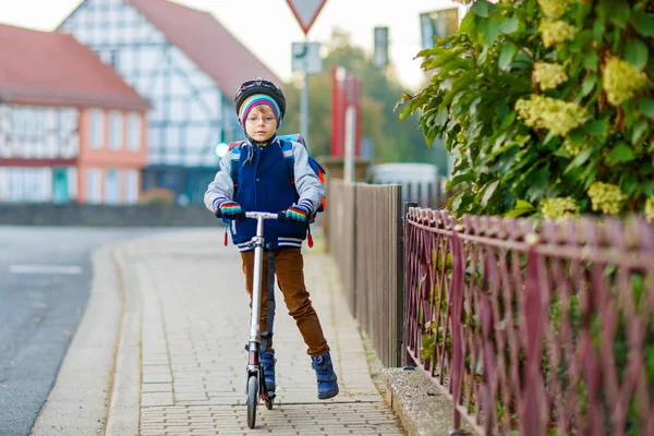 Kleiner Junge mit Helm fährt mit seinem Roller durch die Stadt — Stockfoto