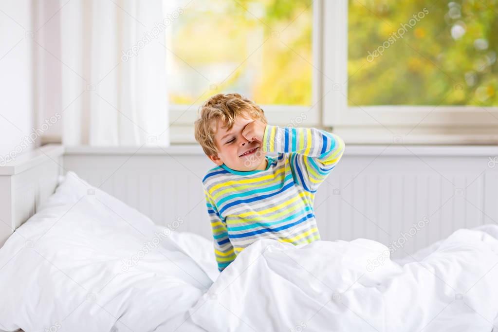 happy little kid boy after sleeping in bed in colorful nightwear