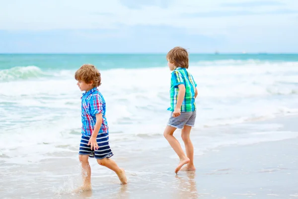 Dos niños pequeños corriendo en la playa del océano — Foto de Stock