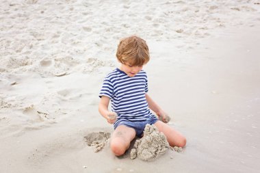 Küçük çocuk çocuk kumdan kaleler inşa ile eğleniyor