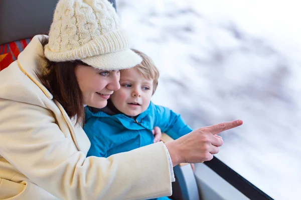 Cute little toddler boy and mother looking out train window making winter vacations — Stock Photo, Image