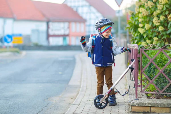 Маленький хлопчик в шоломі їде зі своїм скутером у місті — стокове фото