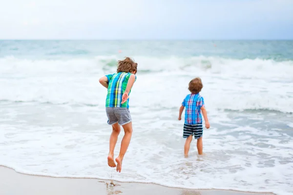 Dwa małe dzieci chłopców uruchomiona na plaży oceanu — Zdjęcie stockowe