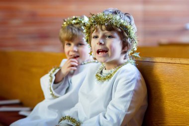 Two little boys as angels of Christmas story eve in church clipart