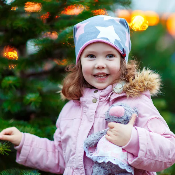 Beautiful smiling little girl holding christmas tree — Stock Photo, Image