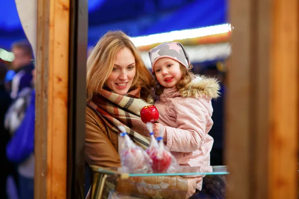 Mère et petite fille mangeant des pommes cristallisées sur le marché de Noël en Allemagne — Photo