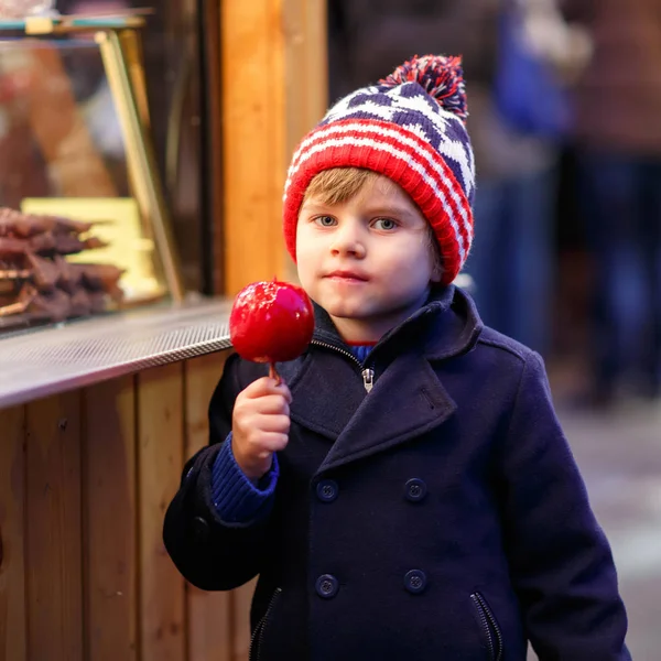 Kleine jongen jongen eten van zoete appel op Duitse kerstmarkt — Stockfoto