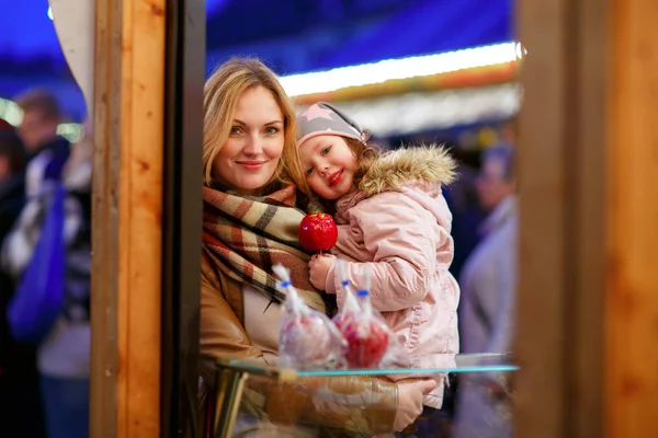 Mère et petite fille mangeant des pommes cristallisées sur le marché de Noël en Allemagne — Photo