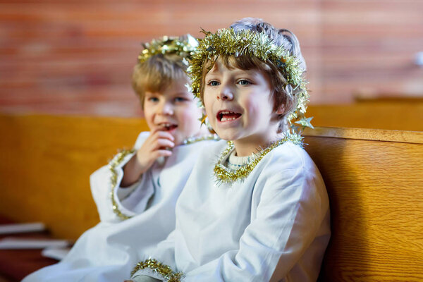 Two little boys as angels of Christmas story eve in church