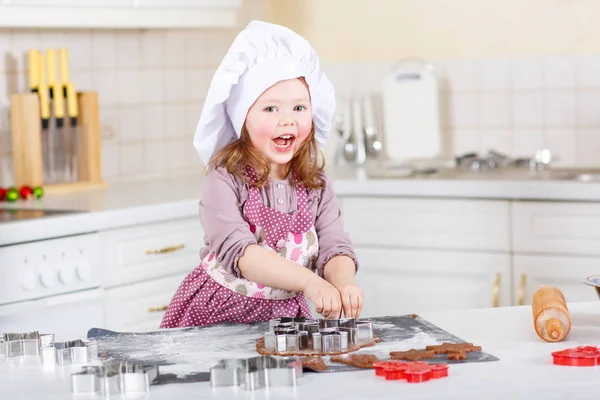Malá holčička pečení perníku cookie v domácí kuchyni — Stock fotografie