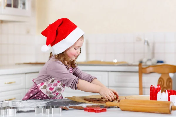 Liten flicka baka pepparkakor i inhemska kök — Stockfoto