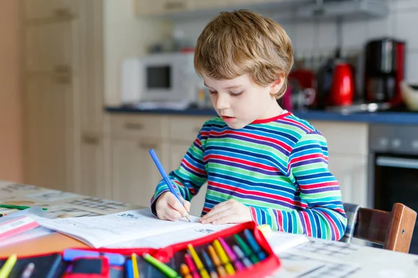Glad skolpojke hemma gör läxor — Stockfoto