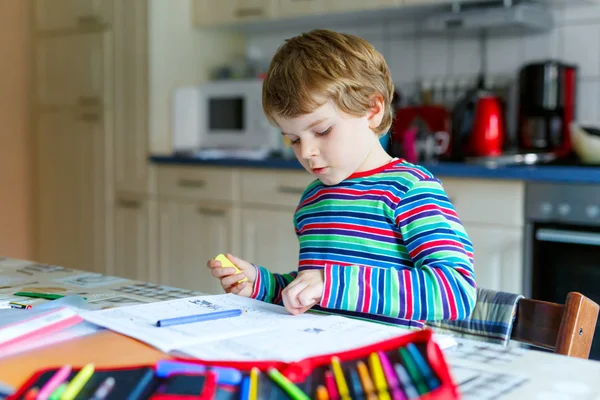 Glücklicher Schuljunge zu Hause, der Hausaufgaben macht — Stockfoto