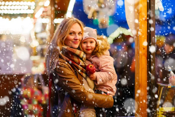Mother and little girl eating crystalized apple on Christmas market in Germany — Stock Photo, Image