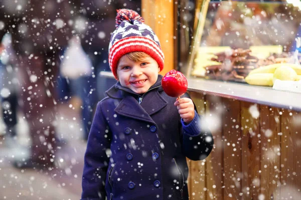 Niño pequeño comiendo manzana dulce en el mercado de Navidad — Foto de Stock