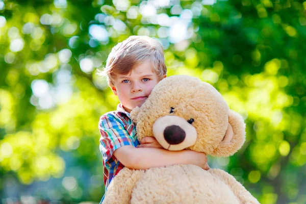 Petit garçon jouant avec un gros ours en peluche, à l'extérieur . — Photo