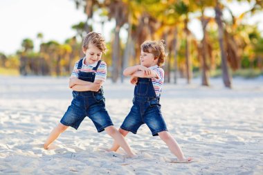 İki küçük çocuk tropik sahilde eğleniyor.