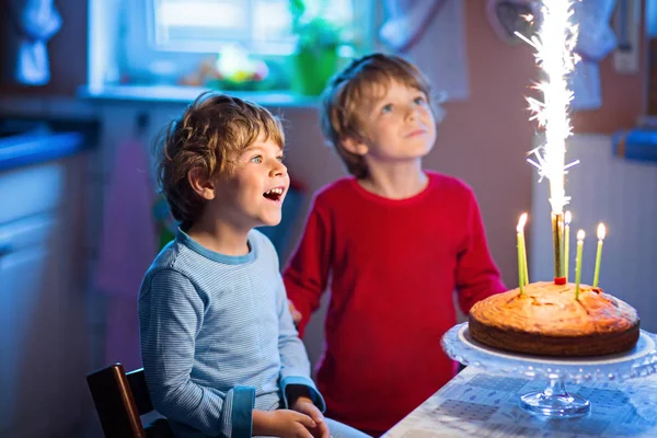 Маленькі хлопчики-близнюки святкують день народження і дме свічки на торт — стокове фото