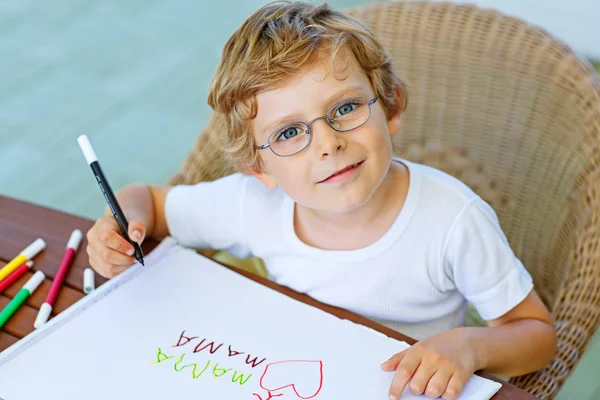 Niño pequeño con gafas haciendo deberes en casa —  Fotos de Stock