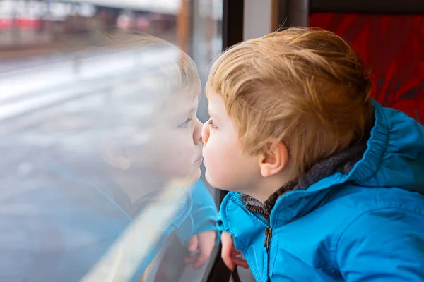 Niedliches kleines Kleinkind, das aus dem Zugfenster schaut — Stockfoto