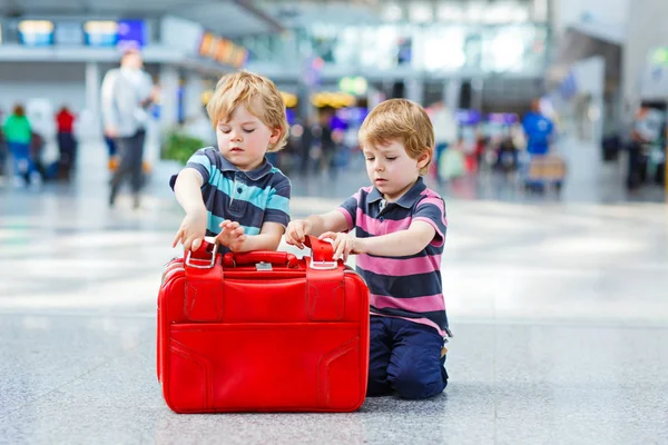 Двоє маленьких хлопчиків їдуть у відпустку з валізою в аеропорту — стокове фото