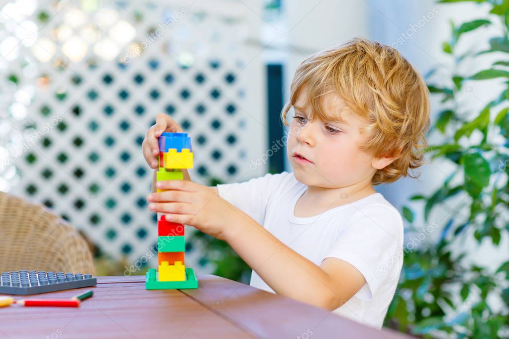 Little kid boy playing with colorful plastic blocks