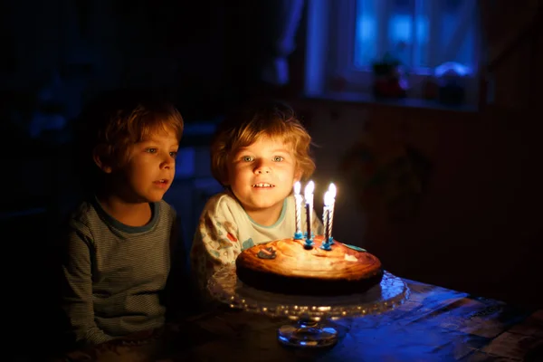 小家伙男孩双胞胎庆祝生日，蛋糕上吹蜡烛 — 图库照片