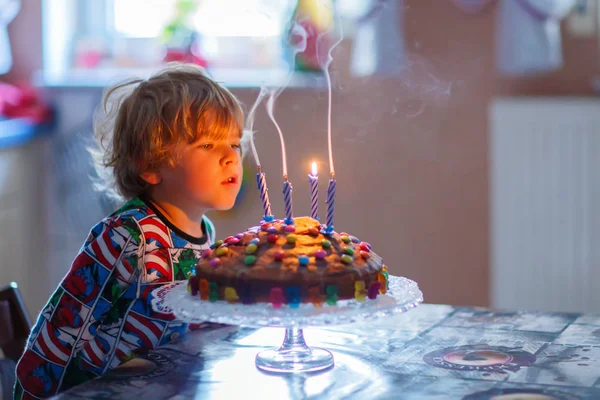 Onun doğum günü kutluyor ve üfleme küçük çocuk çocuk kek üzerine mumlar — Stok fotoğraf