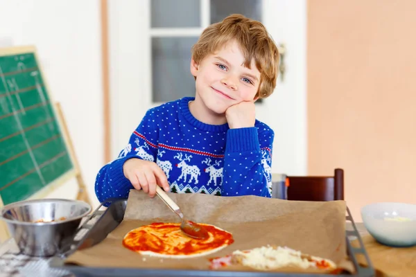 Милый маленький мальчик делает итальянскую пиццу из свежих овощей — стоковое фото