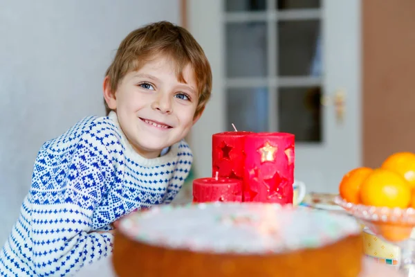 Kleiner Junge steht zur Weihnachtszeit am Fenster und hält — Stockfoto