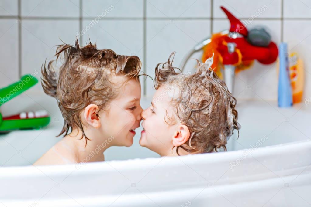 Two little kids boys playing together in bathtub