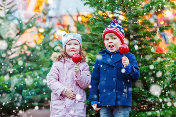 Двое маленьких детей едят сахарное яблоко на Рождественской ярмарке — стоковое фото