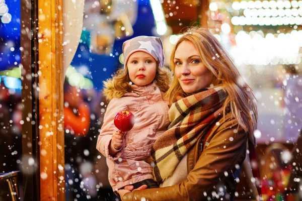 Woman and little girl eating crystalized apple on Christmas mark — Stock Photo, Image