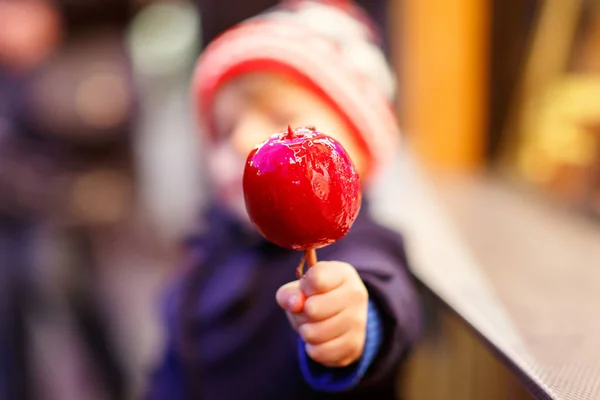 Menino pequeno comendo maçã doce no mercado de Natal — Fotografia de Stock