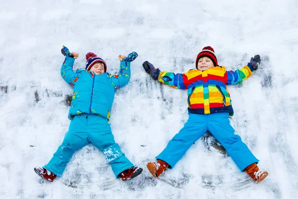 Two little kid boys making snow angel in winter, outdoors — Stock Photo, Image