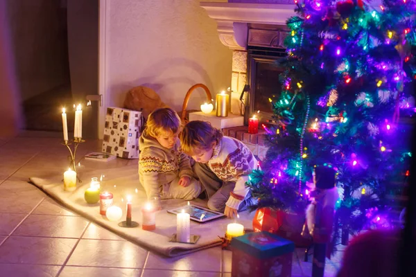 Duas crianças sentadas em uma lareira em casa no Natal — Fotografia de Stock