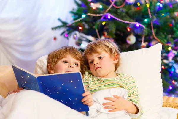 Due fratellini biondi che leggono un libro sul Natale — Foto Stock