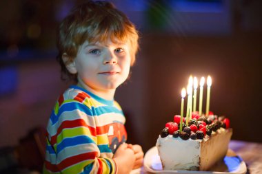 Onun doğum günü kutluyor ve üfleme küçük çocuk çocuk kek üzerine mumlar