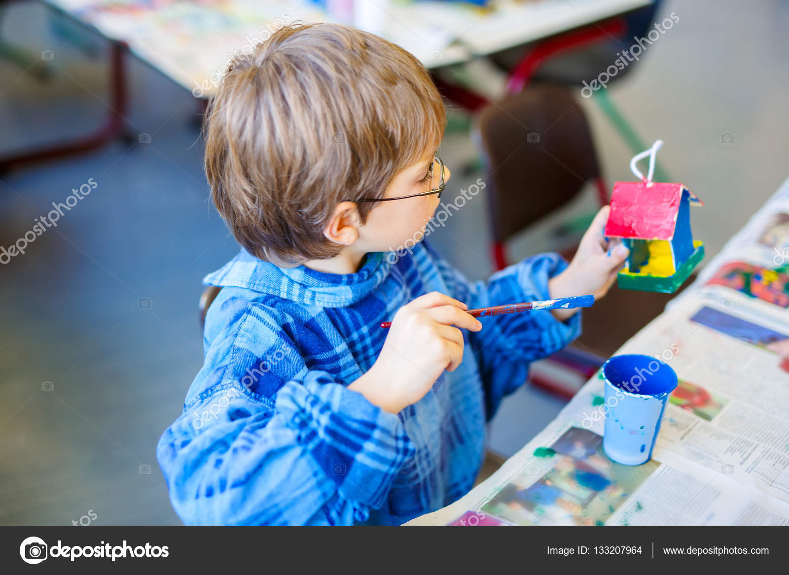 Piccolo ragazzo del bambino scuola con occhiali colorare la casa Ragazzino ragazzo scuola con occhiali colorare la casa di uccello con gli acquerelli in aula di manodopera bambino che ha divertimento con l apprendimento