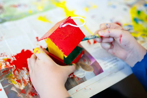 Primer plano de las manos del niño para colorear casa de aves con acuarelas —  Fotos de Stock