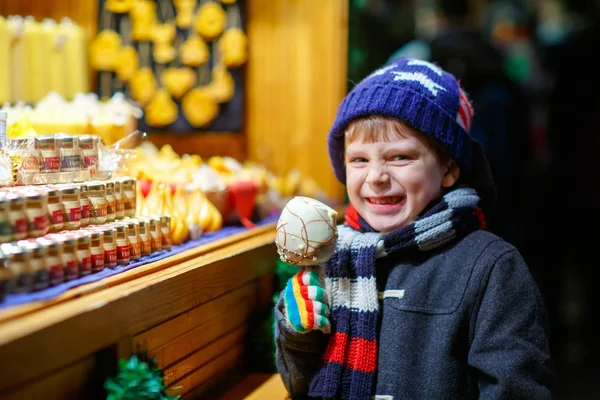 Kleiner Junge isst Zuckerapfelbonbons Stand auf dem Weihnachtsmarkt — Stockfoto