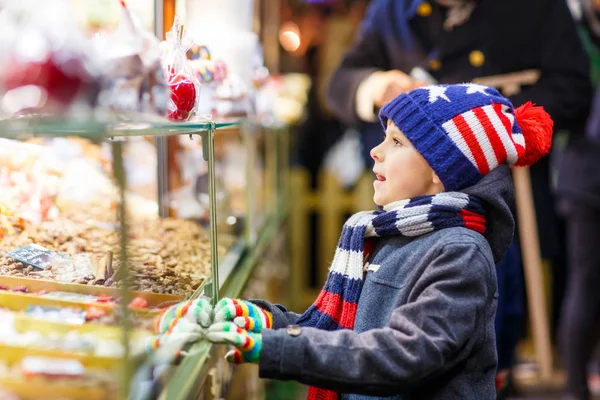 Маленький мальчик с пряниками и сладостями стоит на рождественской ярмарке Лицензионные Стоковые Фото
