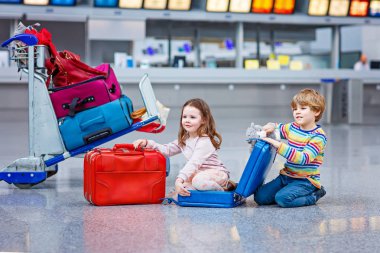 Two little kids, boy and girl going on vacations trip with suitcase at airport clipart