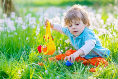 Küçük çocuk geleneksel Paskalya yumurtası avında eğleniyor.